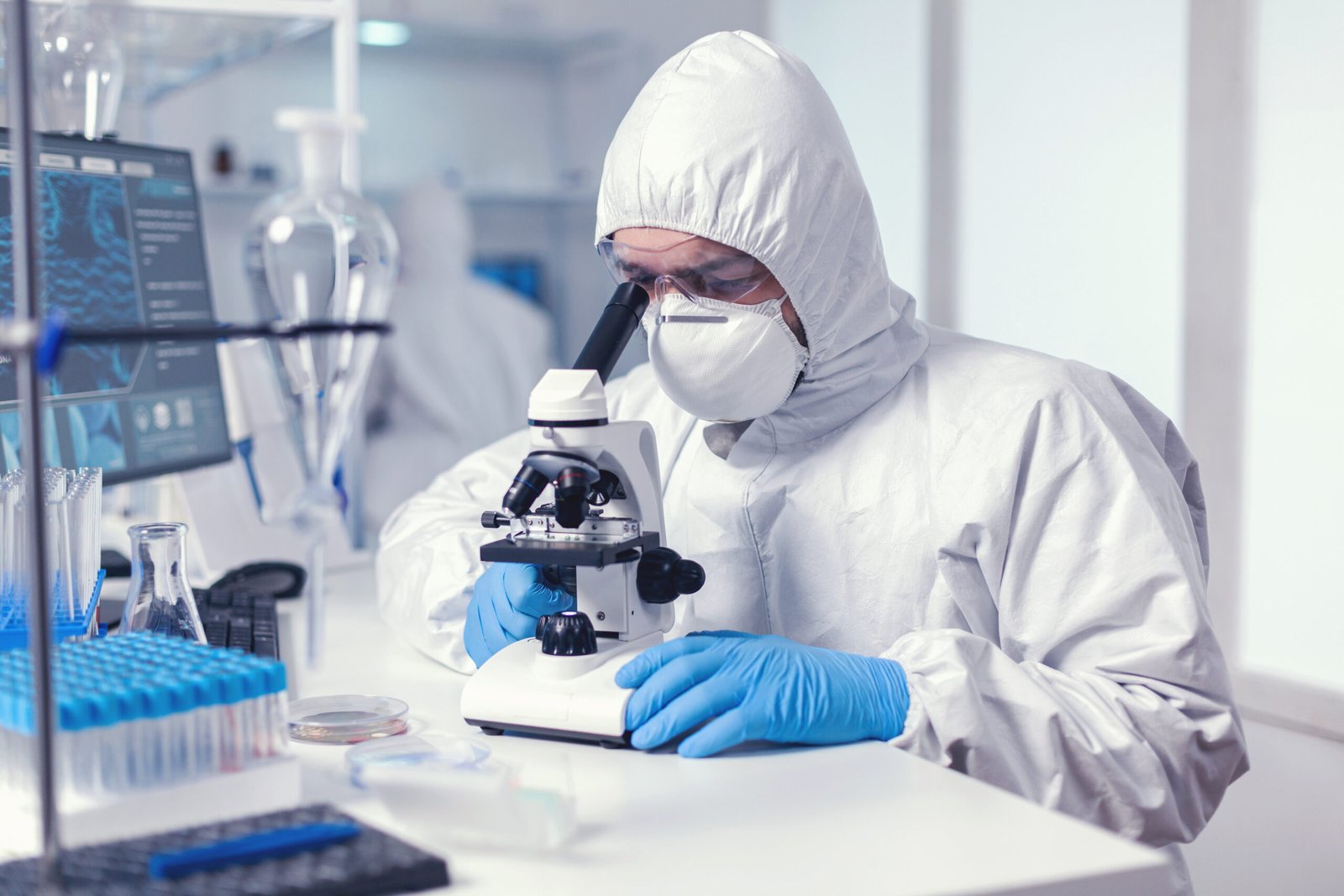 Microbiologist with protection glasses using microscope